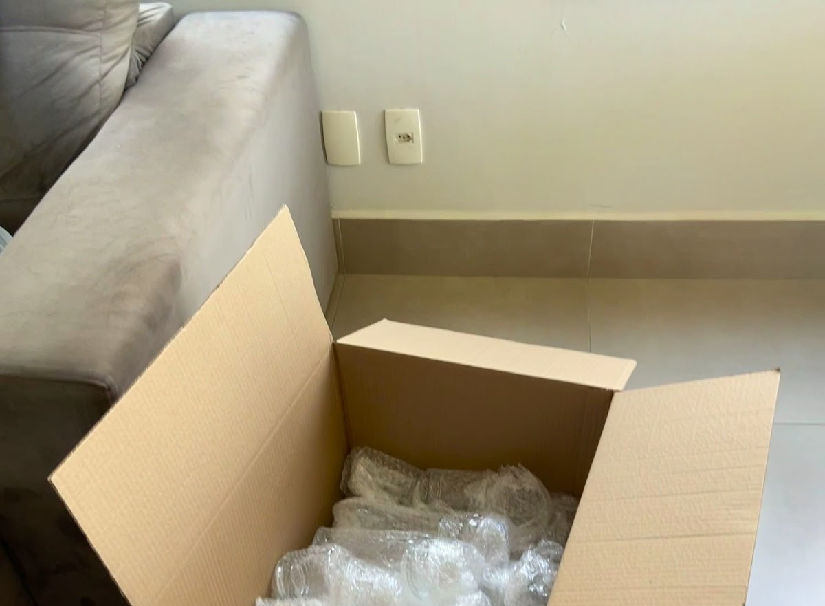 Caixa de papelão aberta com copos envolvidos em plástico bolha